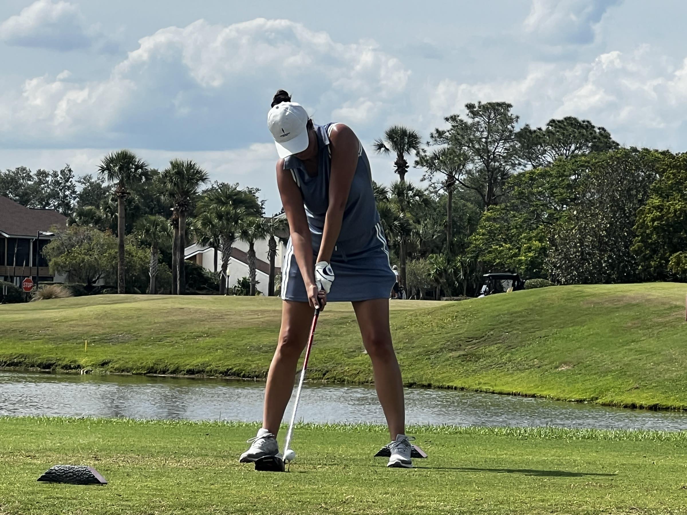 A golfer preparing to play beside the water